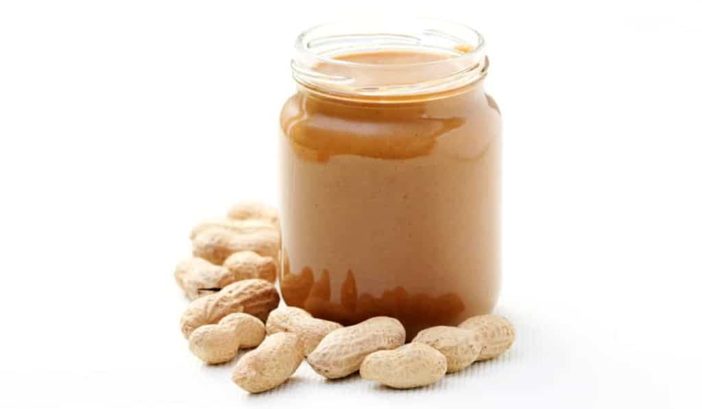 Can German Shepherds Eat Peanut Butter? Jar of Peanut Butter surrounded by peanuts