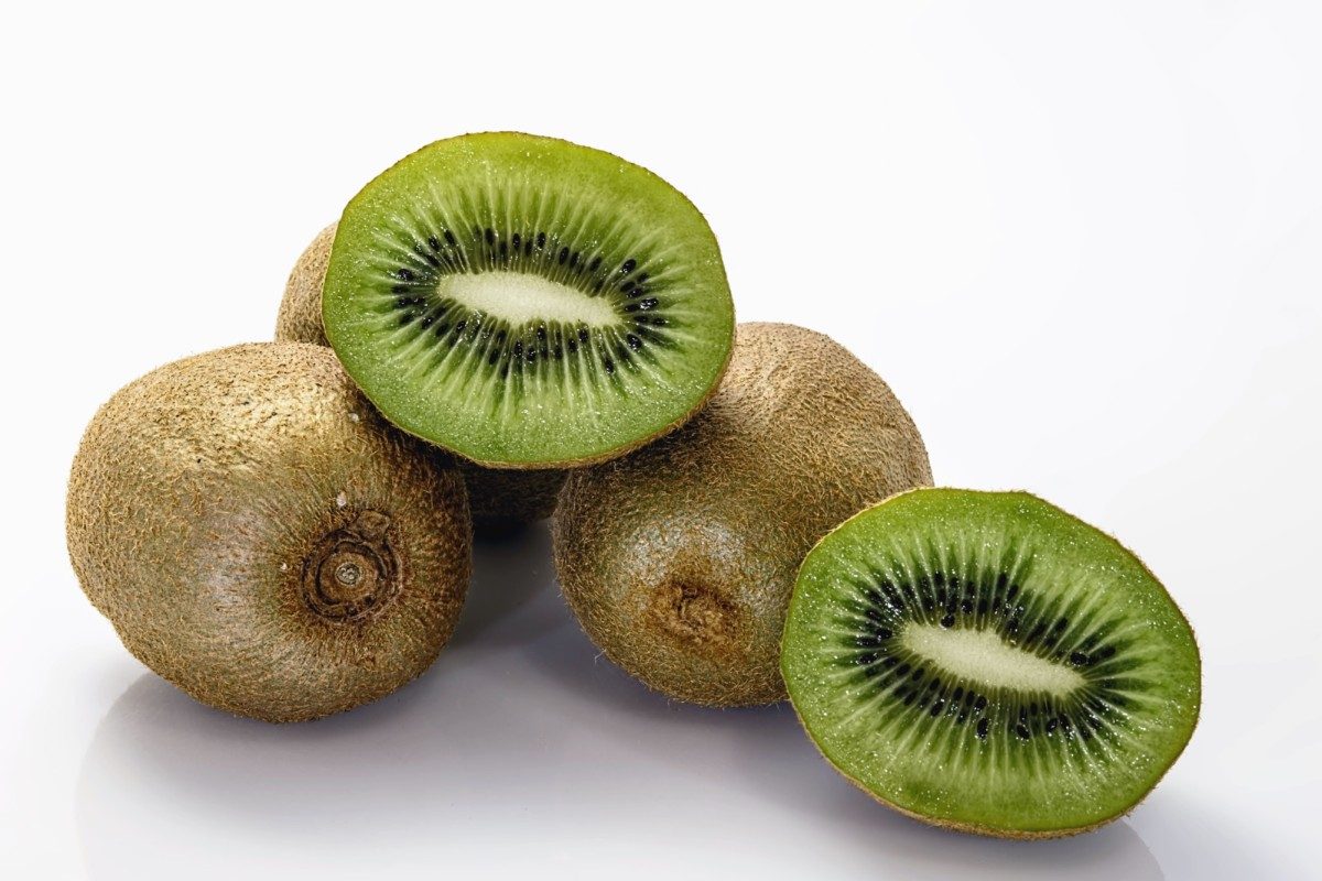 Multiple Kiwis placed on the table with one of them cut into two halves